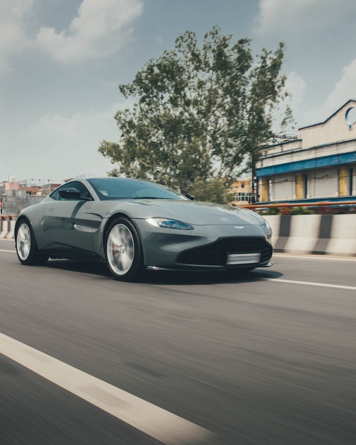 A sleek sports car speeds through a sunny Delhi street, capturing the essence of luxury and motion.